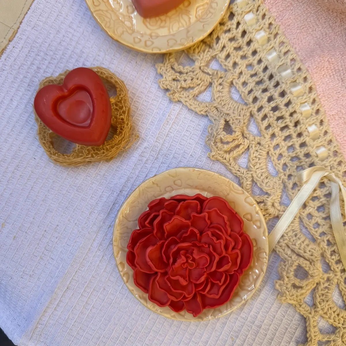Jabones con forma de flor y corazón sobre jaboneras de cerámica